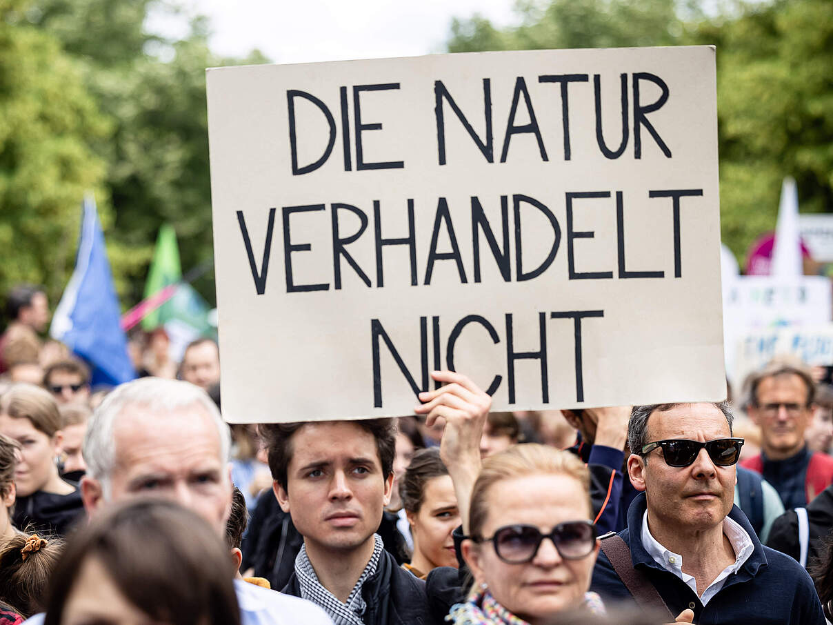 Ein Mann in einer Menschenmenge beim Klimastreik hält ein Schild. Darauf steht: Die Natur verhandelt nicht. 