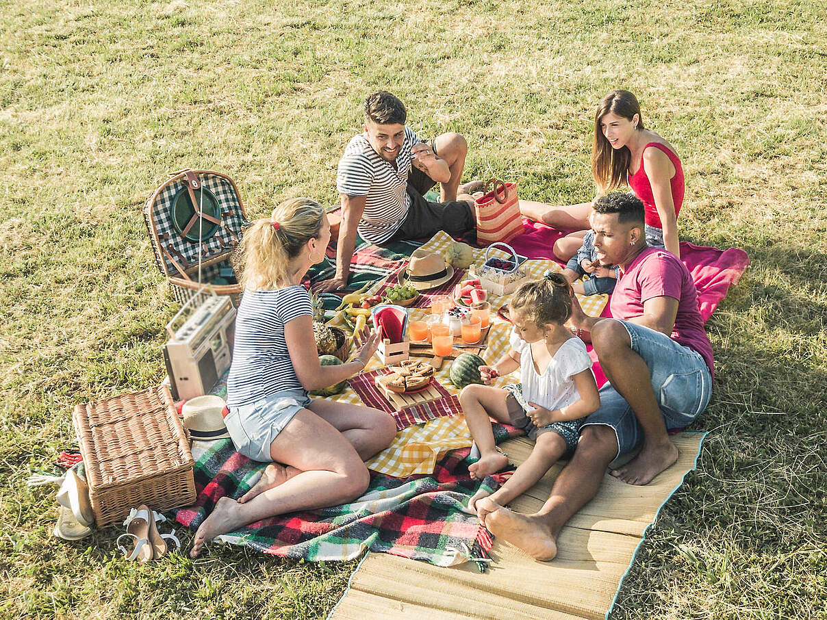Eine Gruppe von Menschen picknickt im Park © GettyImages